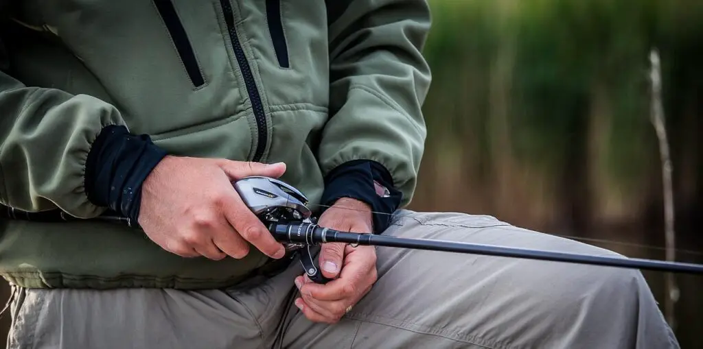 A man wearing a jacket holding his baitcasting rod