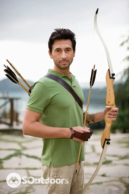 A grown man preparing his arrow to be used on his bow