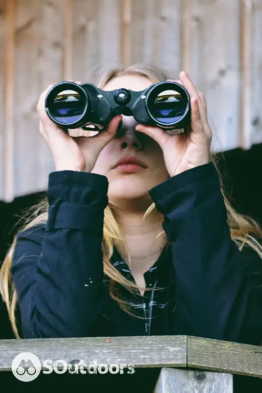 A young blonde female testing a binocular