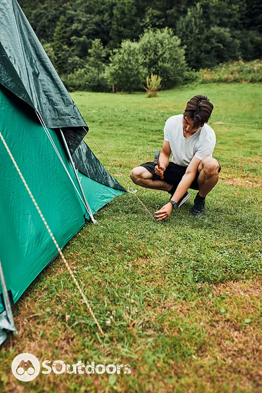 Young man putting up a stable tent on camping during summer vacation trip