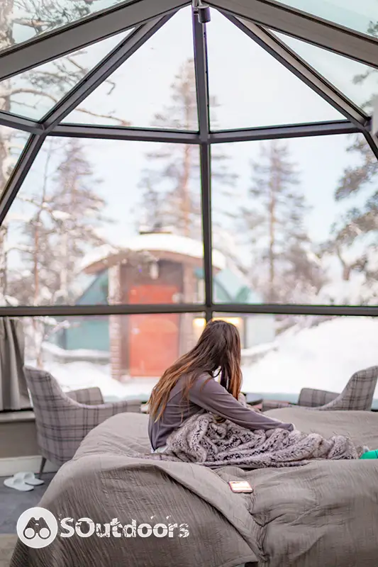 A female who just woke up from her bed looking through her transparent dome tent