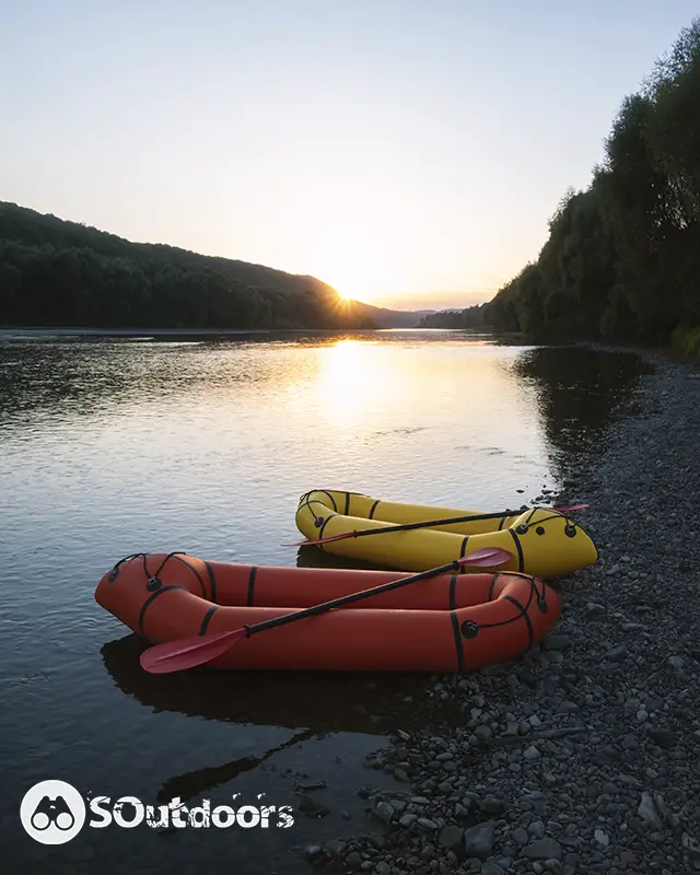 Orange and yellow inflatable fishing kayaks with padles on a sunrise river.
