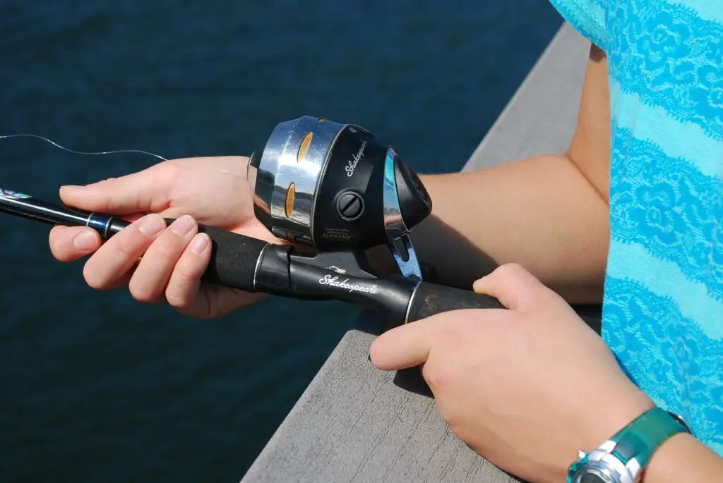 A fishing rod with spincast reel held by a teenager