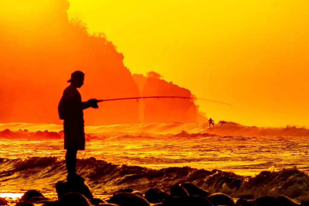 A man holding his fishing near the sea on a yellowish background