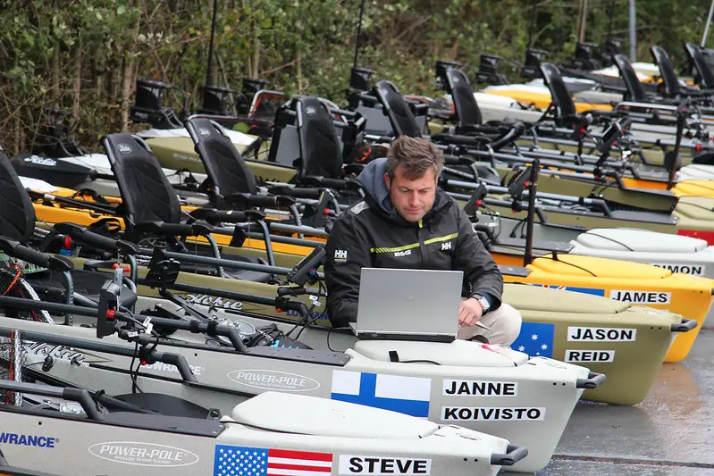 A man using his laptop on top of a kayak mounted with side imaging devices